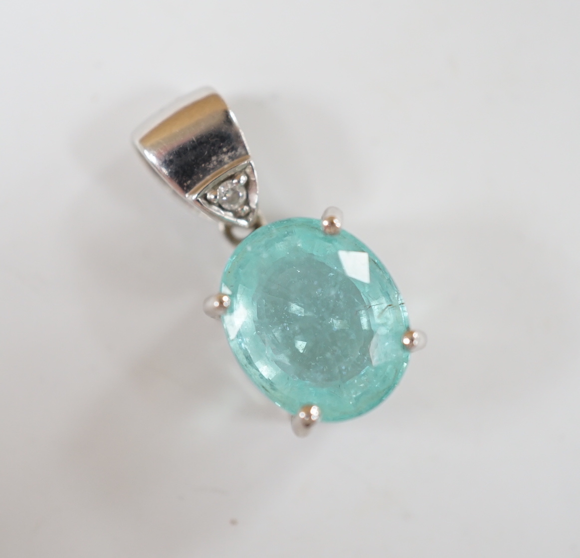 An 18ct white gold and single stone oval cut paraiba tourmaline pendant, with single stone diamond set bale, overall 19mm, gross weight 3.7 grams.